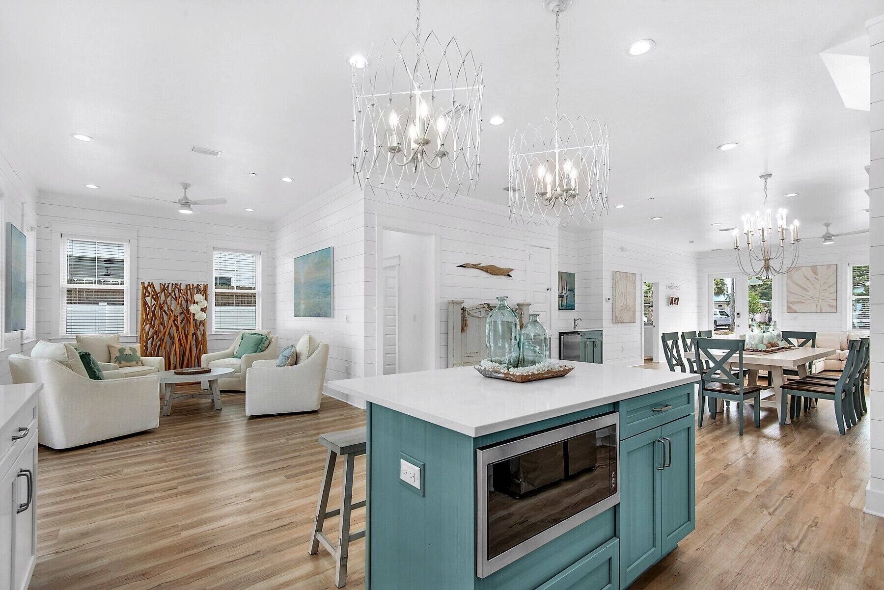 Une cuisine spacieuse dotée d’un îlot central, de meubles de couleur turquoise et d’un éclairage moderne suspendu au plafond.
