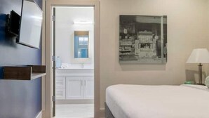 A bedroom with a bed, a nightstand, a lamp, and a wall-mounted TV. - Unit 201 2BR Walk to Bourbon Street! (New Orleans)