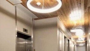 A modern hallway with a circular light fixture, an elevator, and a door with a keypad lock. - Unit 201 2BR Walk to Bourbon Street! (New Orleans)
