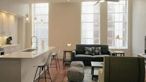 Et moderne køkken med en central ø, barstole, en sofa og et spiseområde.
