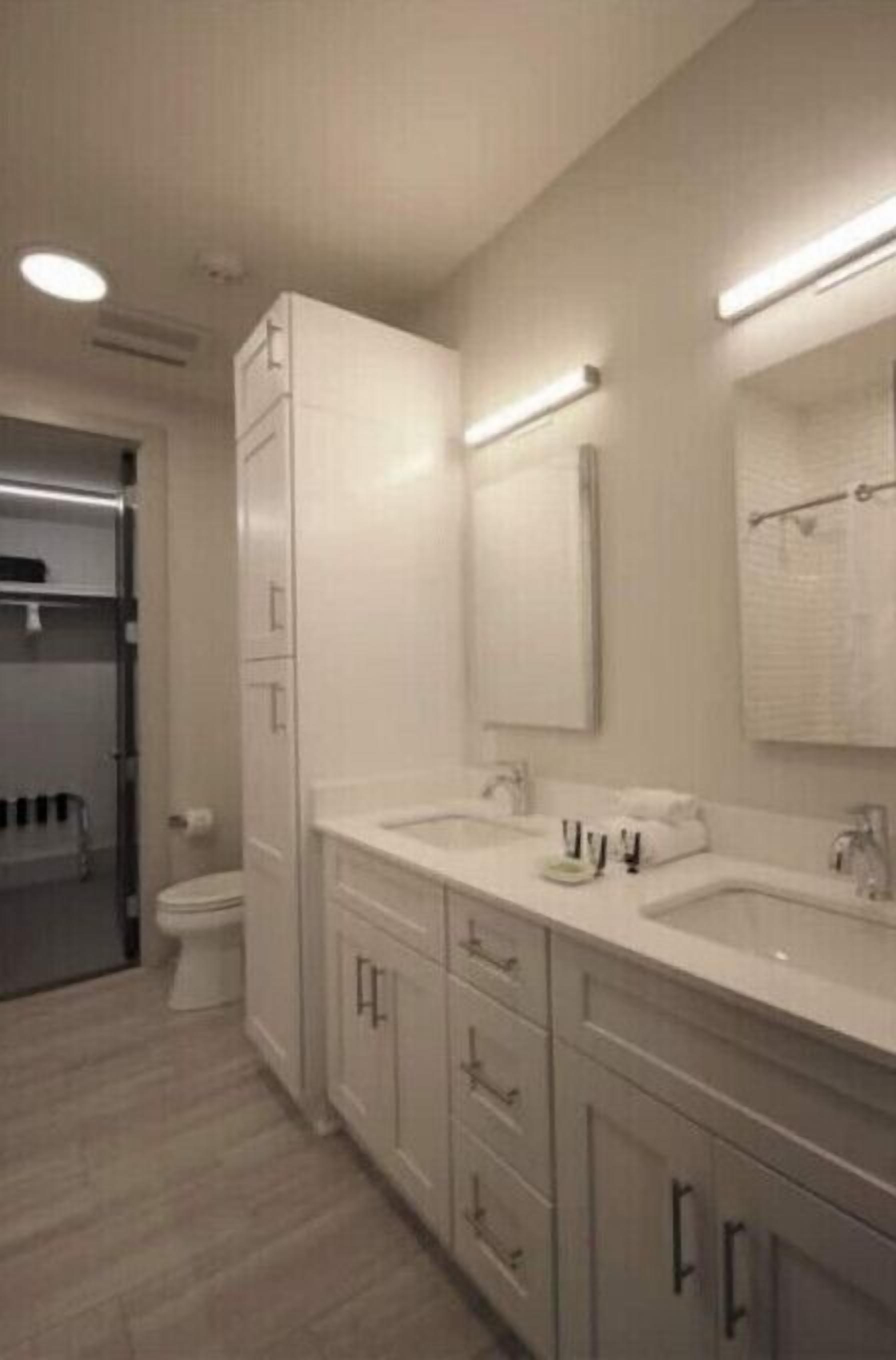 Un bagno moderno con due lavabi, un water e una zona doccia.