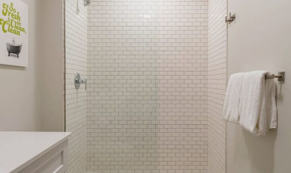 A bathroom with white subway tiles, a white sink, and a towel rack with a white towel.