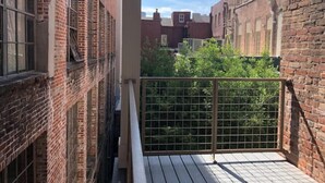 A narrow alleyway with brick buildings on either side, a metal gate, and a wooden deck.