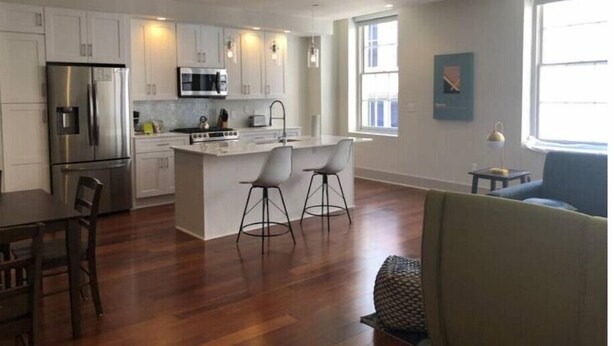 A modern kitchen with white cabinets, stainless steel appliances, and a central island with bar stools.