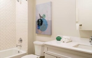 Ein Badezimmer mit einer weißen Badewanne, einer Toilette, einem Waschbecken und einem Handtuch auf der Ablagefläche.