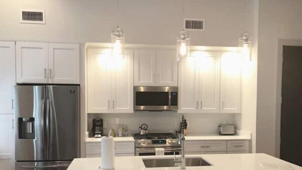 A modern kitchen with white cabinets, stainless steel appliances, and a central island with seating. - Close to Hospitals & close to the French Quarter! 2BR Unit 202 (New Orleans)