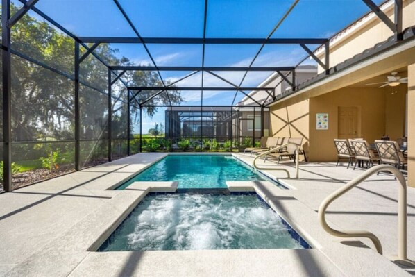 Uma área de piscina com hidromassagem, espreguiçadeiras e um espaço de estar coberto.