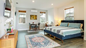 A bedroom with a bed, desk, chair, and a large window.