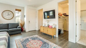 A living room with a sofa, a TV, a clock, and a patterned rug.
