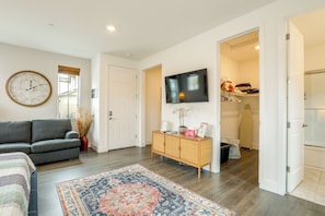 A living room with a sofa, a TV, a clock, and a patterned rug. - 3 Mi to Golf & Shopping: Cozy Roseville Studio (Roseville)