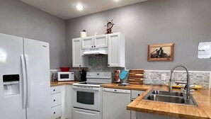 Een moderne keuken met witte kastjes, een houten aanrecht, een roestvrijstalen spoelbak en een magnetron.