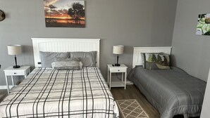 Een slaapkamer met een groot bed, twee nachtkastjes, een vloerkleed en een schilderij aan de muur.