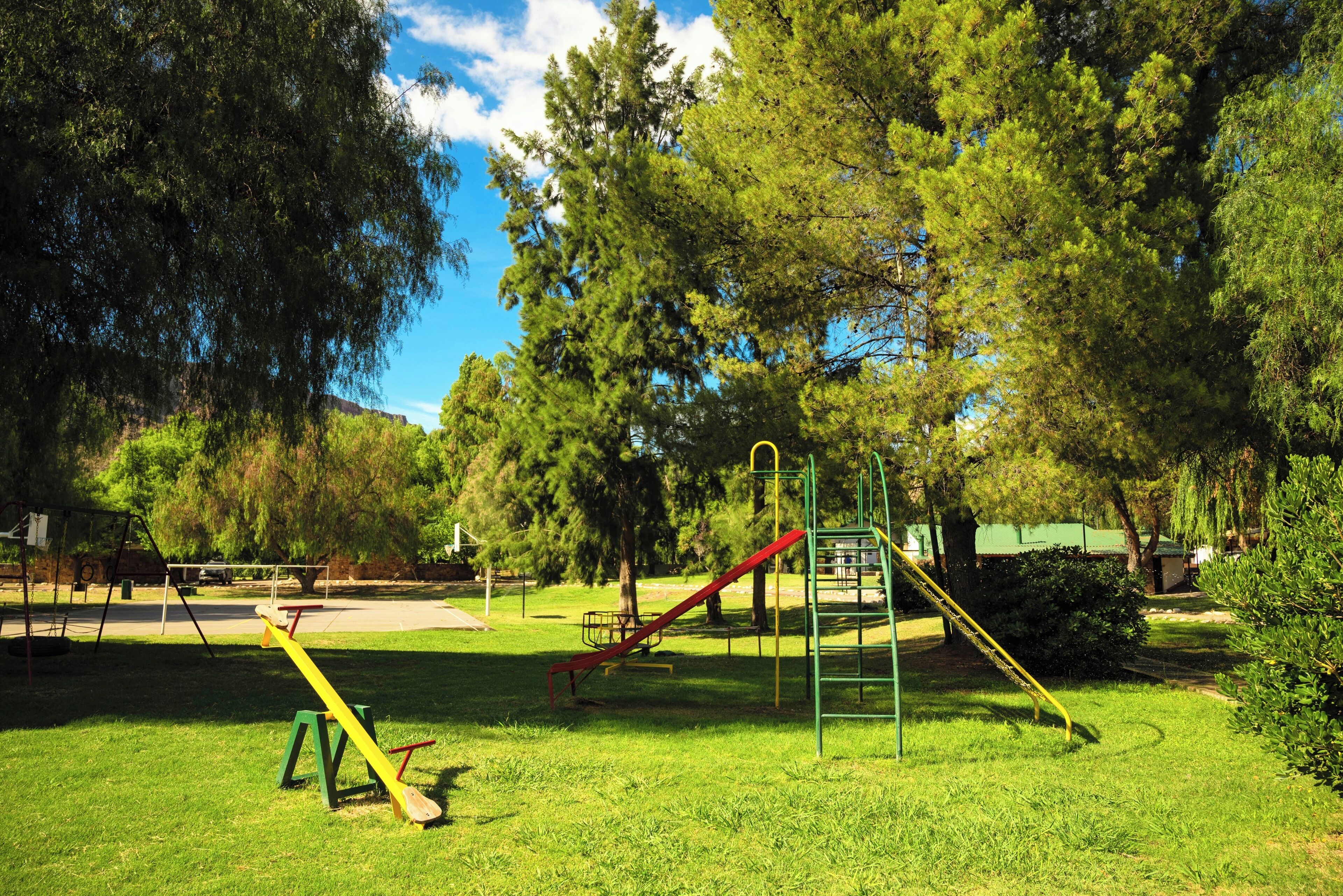 Une aire de jeux avec des balançoires, un toboggan et des structures d’escalade.