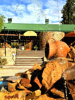 A stone building with a green roof, a large terracotta pot, and a stone staircase leading to a door. - HOTEL VALLE GRANDE (El Nihuil)