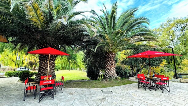 Une terrasse extérieure avec un sol en pierre, des parasols rouges et des sièges d’extérieur.