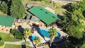 Vue aérienne d’un complexe hôtelier doté d’une piscine, de palmiers et d’un bâtiment dont le toit est végétalisé.