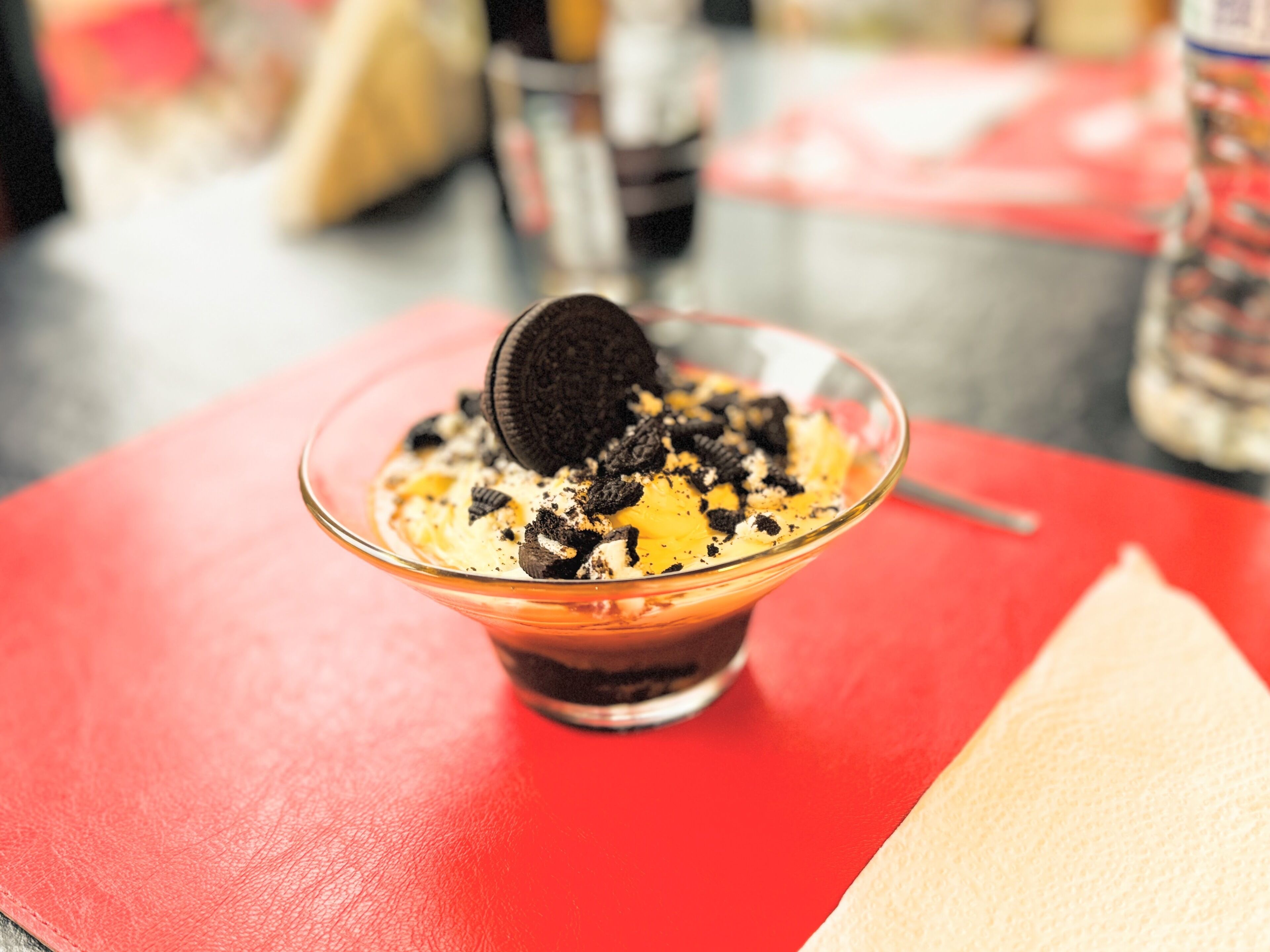 A dessert in a clear glass bowl on a red table.