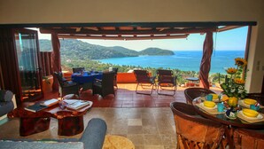 Una terraza con vista al océano, amueblada con sillas y una mesa de comedor.