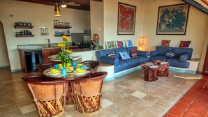 Un salón amplio con un sofá azul, una mesa de comedor con sillas y una cocina al fondo.