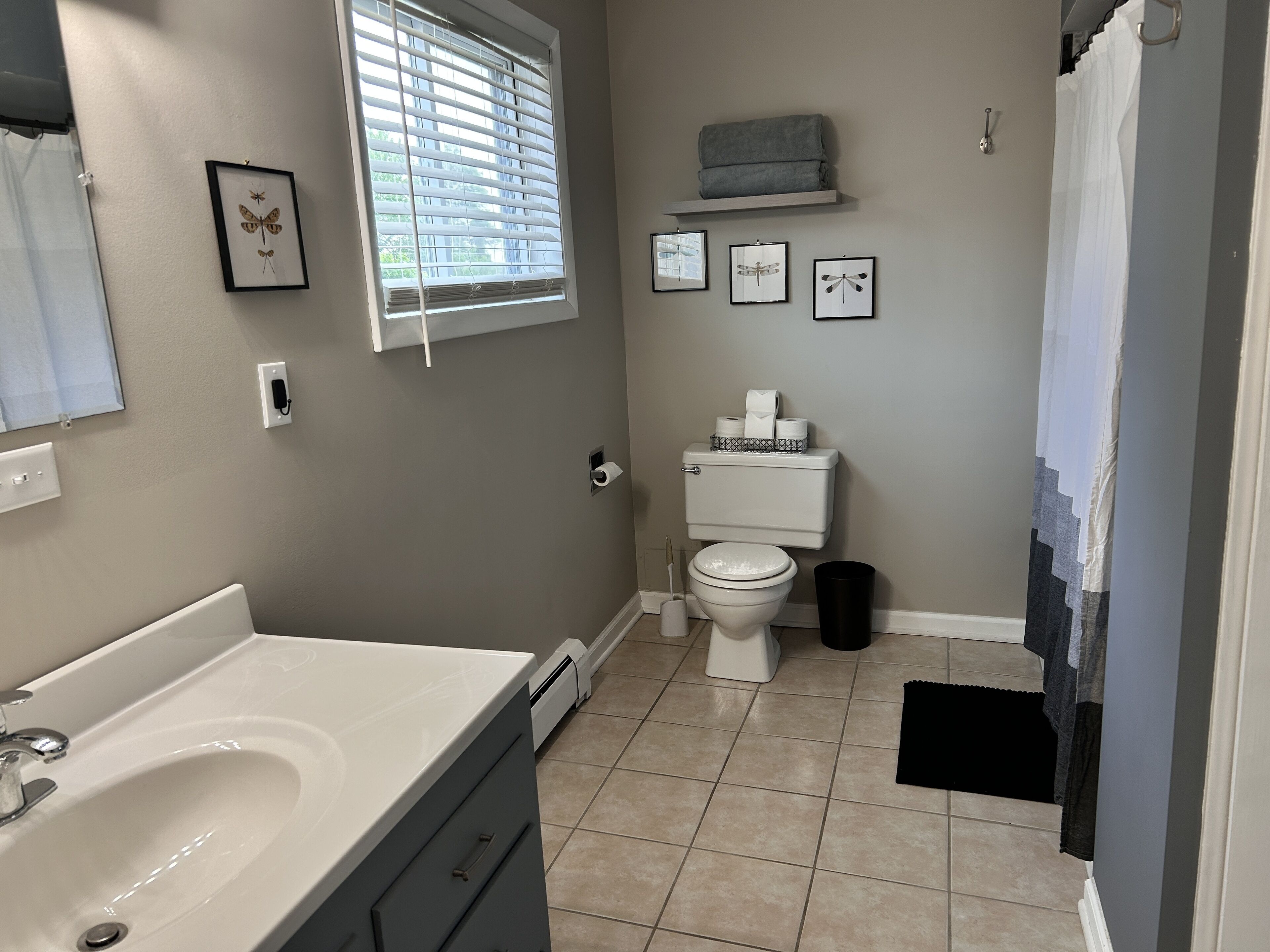 A bathroom with a white sink, toilet, and window with blinds.