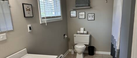 A bathroom with a white sink, toilet, and window with blinds.