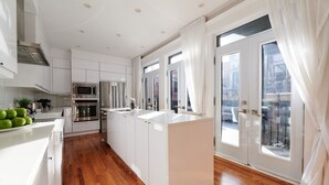 A modern kitchen with white cabinetry, a central island, and a large window with curtains.