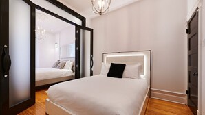 A modern bedroom with a large bed, a mirror, and a chandelier.