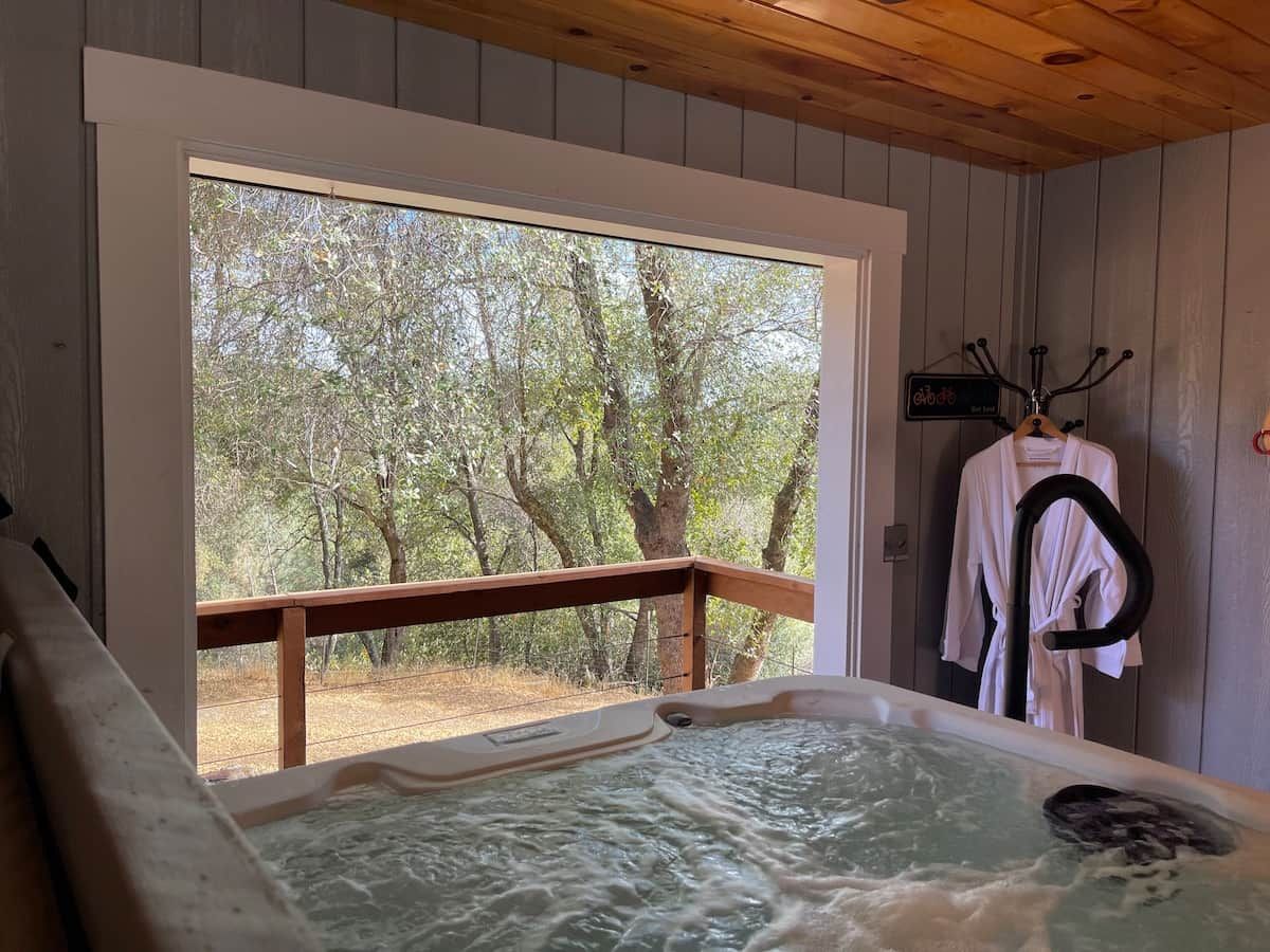 A hot tub with a wooden deck and a view of trees.