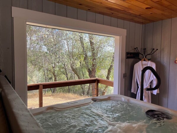 Jacuzzi con cubierta de madera y vista a los árboles.