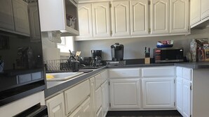 Una cocina con armarios blancos, una estufa negra y un microondas en la encimera.