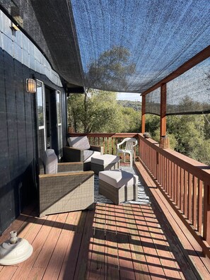 A covered outdoor deck with wicker furniture and a view of the surrounding landscape.
