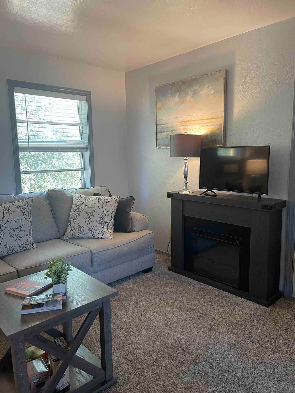 Una sala de estar con sofá, mesa de centro, chimenea y televisor.