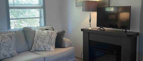 Una sala de estar con sofá, mesa de centro, chimenea y televisor.