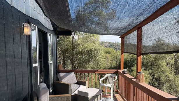 Una terraza al aire libre techada con mobiliario de mimbre y vistas del paisaje circundante.