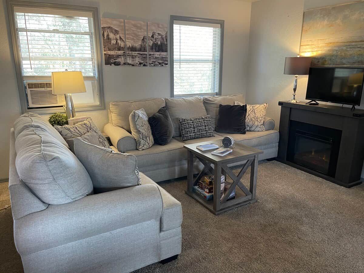 A living room with a sofa, a coffee table, a fireplace, and artwork on the walls.