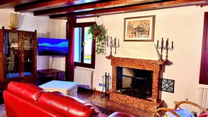 A living room with a red leather sofa, a television, a fireplace, and a framed picture on the wall. - Canal View (Venezia)