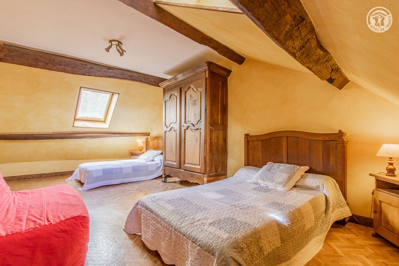 Camera da letto con due letti, un'armadio in legno e un lucernario.