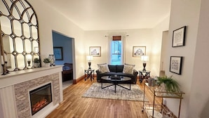 Una sala de estar con chimenea, un sofá, dos mesas auxiliares y una mesa de centro.