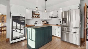 Una cocina moderna con armarios blancos, electrodomésticos de acero inoxidable y una isla central.