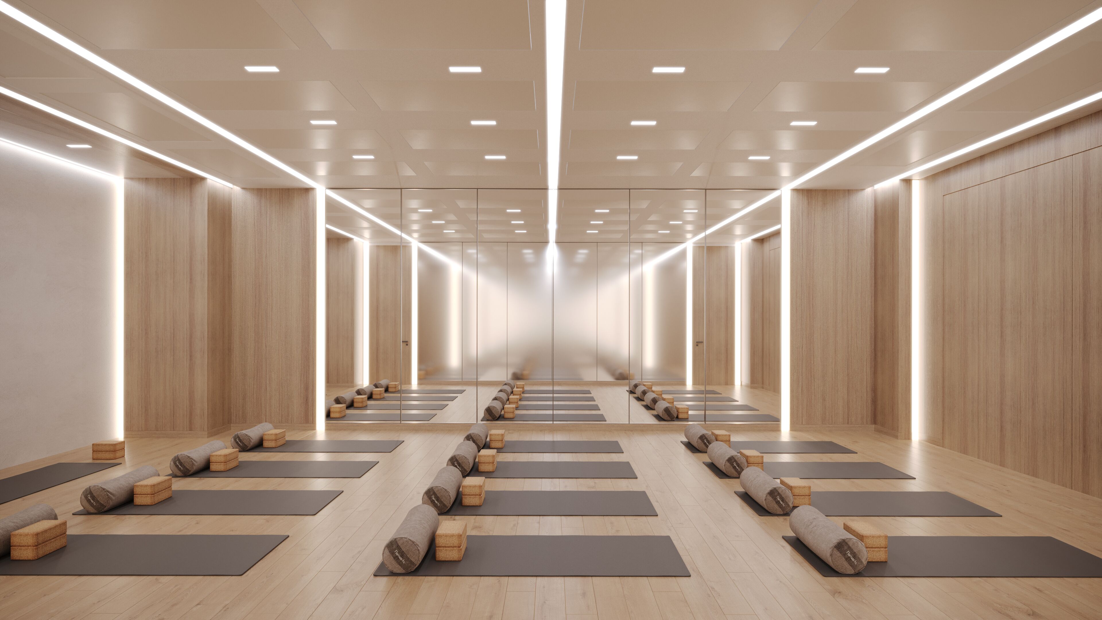 Un amplio estudio de yoga con suelos de madera, esterillas y bloques dispuestos para la práctica.