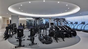 Une salle de sport moderne dotée de divers équipements pour le cardio et le renforcement musculaire, notamment des tapis de course et des appareils de musculation, disposés selon un agencement circulaire.