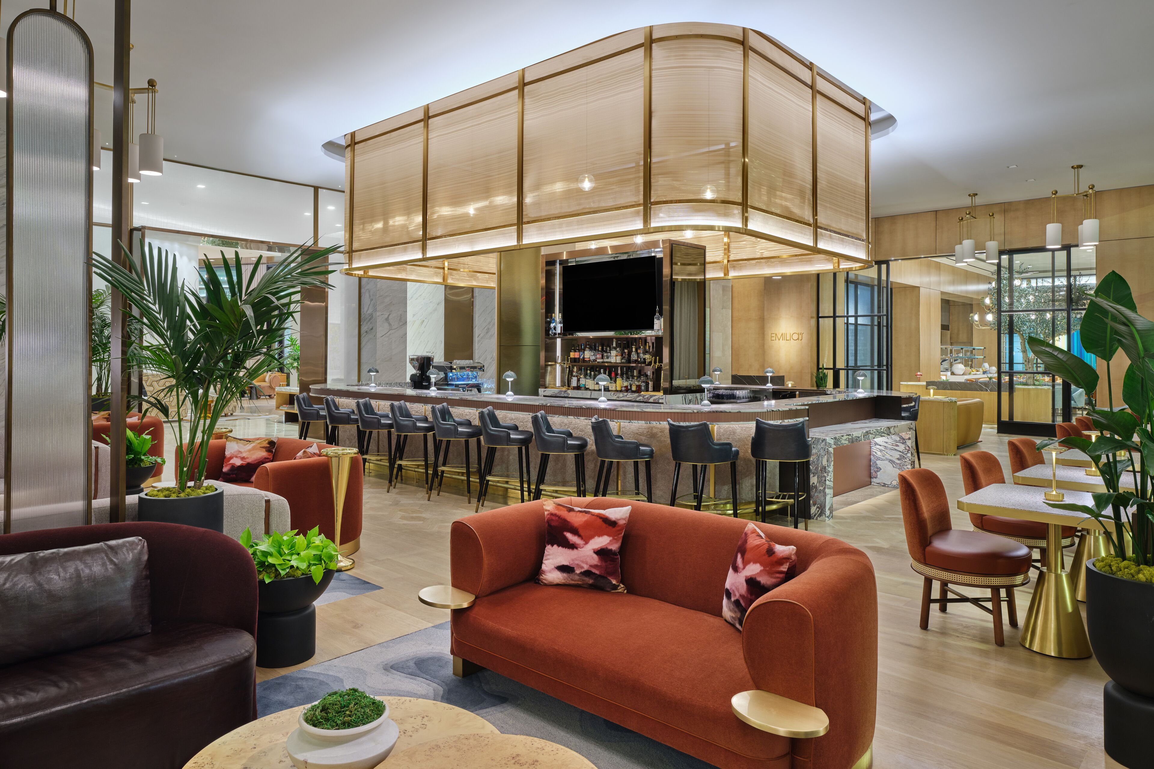 A modern hotel lobby with a bar area, seating arrangements, and a large plant.