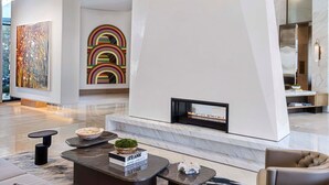 A modern living room with a fireplace, abstract art, and contemporary furniture. - The Crescent Hotel Fort Worth (Fort Worth)