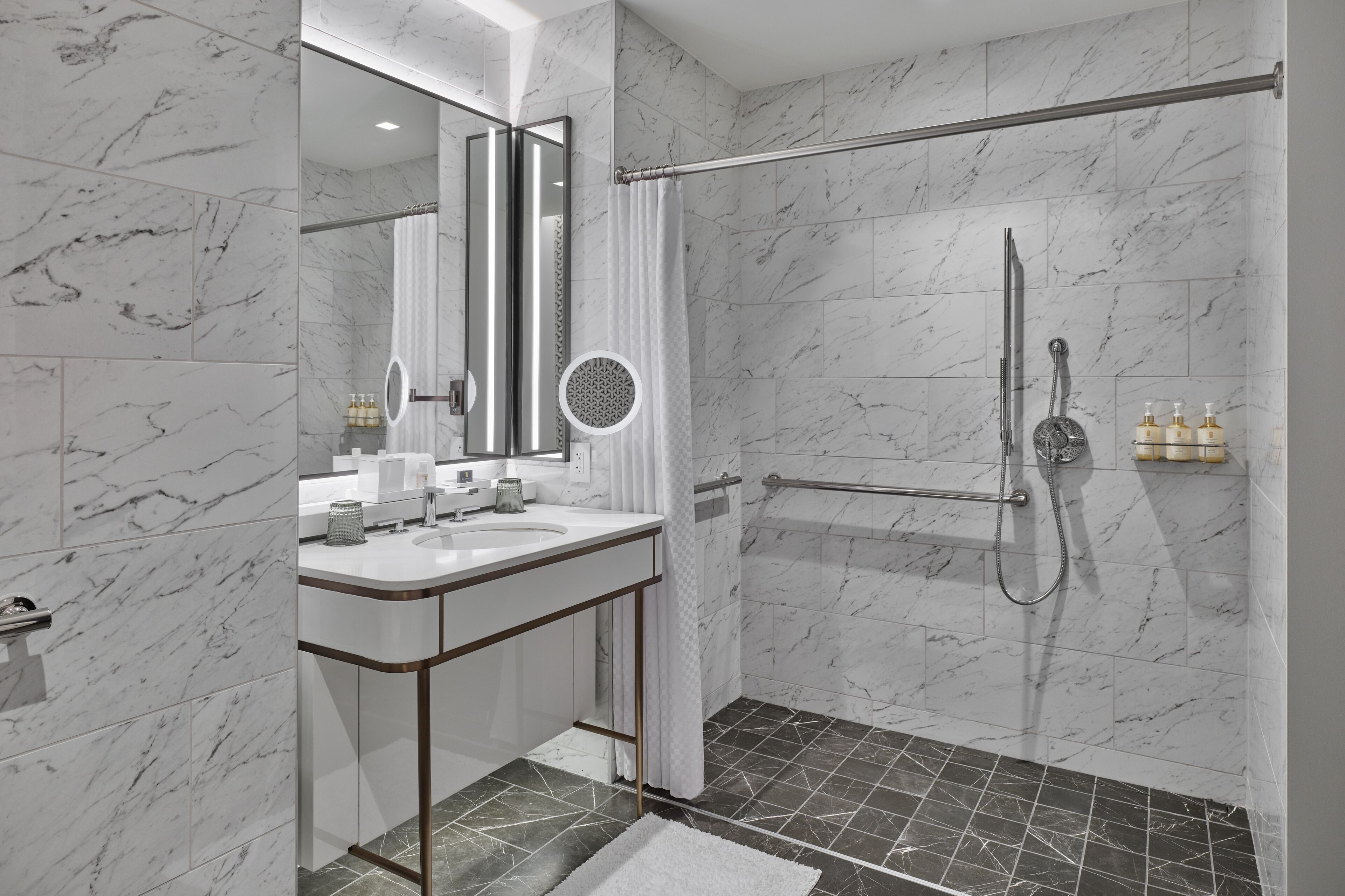 A modern bathroom with a marble shower, a glass-enclosed walk-in shower, and a vanity with a mirror.