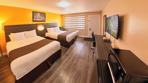A hotel room with two beds, a desk, a television, and a window with blinds.