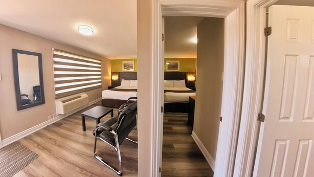Habitación de hotel con cama, escritorio, silla, espejo y radiador.
