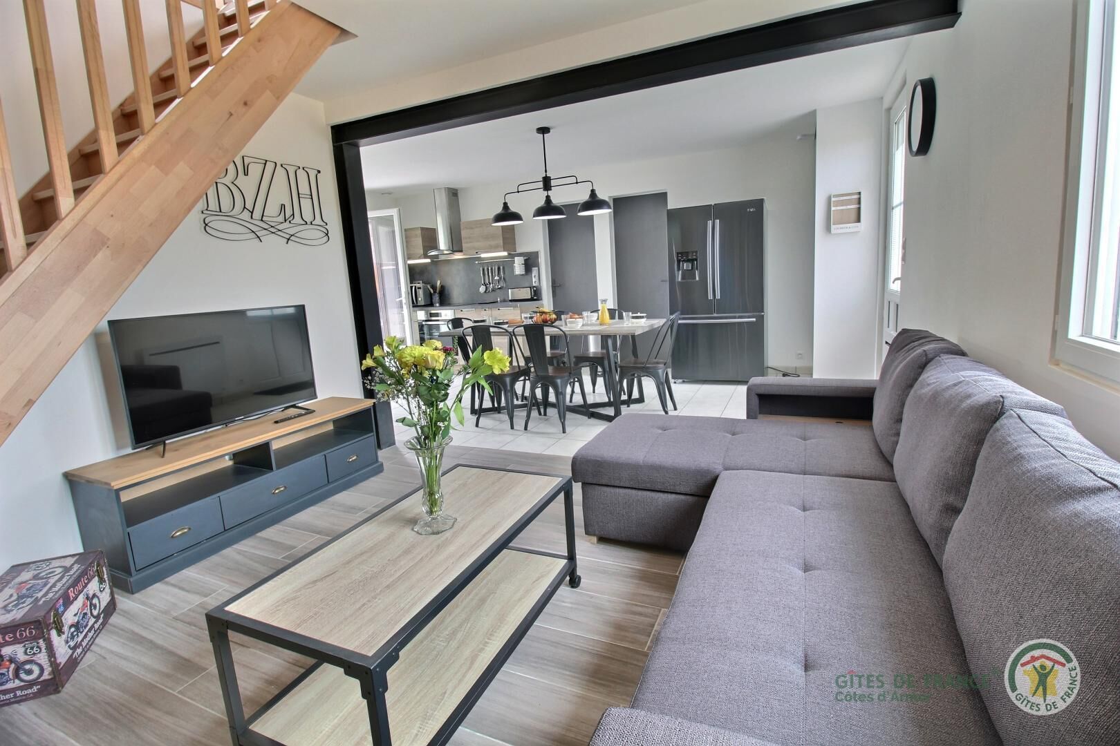 Ein modernes Wohnzimmer mit Fernseher, Sofa und Couchtisch. Eine Treppe führt zu einer weiteren Ebene.