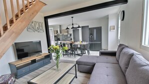 A modern living room with a TV, sofa, and coffee table. There is a staircase leading to another level.