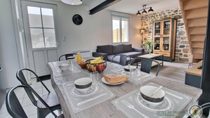 A dining area with a wooden table set for four, a fruit bowl, and a clock on the wall.