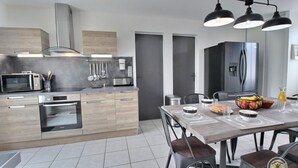 A modern kitchen with stainless steel appliances, a wooden countertop, and a dining area with a table set for two.